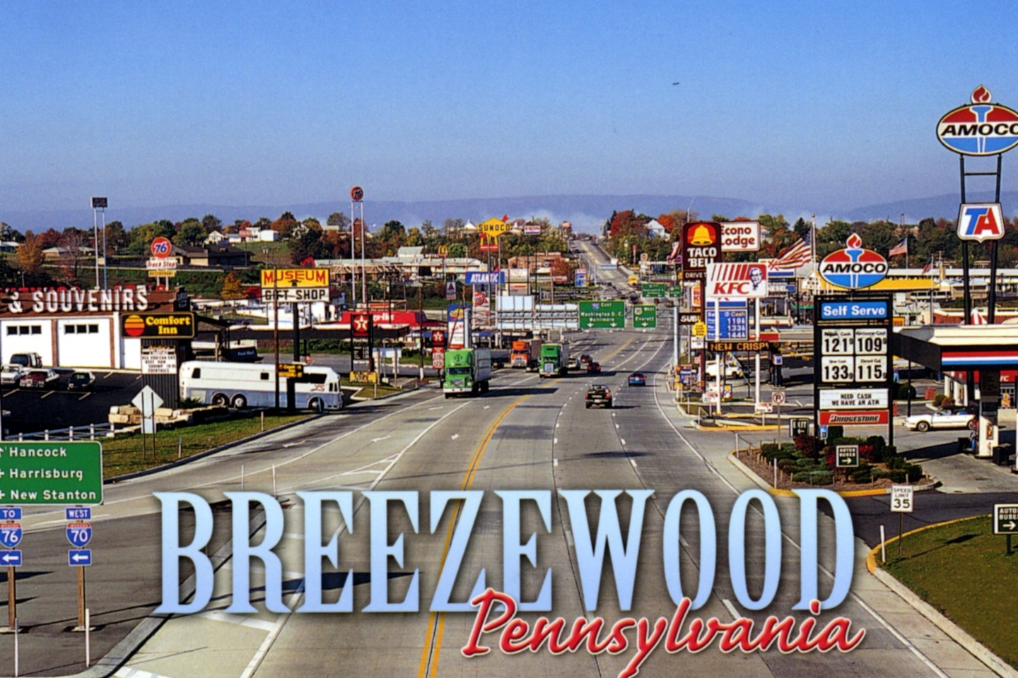 Mock postcard for Breezewood, Pennsylvania, an isometric view of the main drag on a sunny day, with many car- and truck-oriented chain businesses and wide roads and lanes